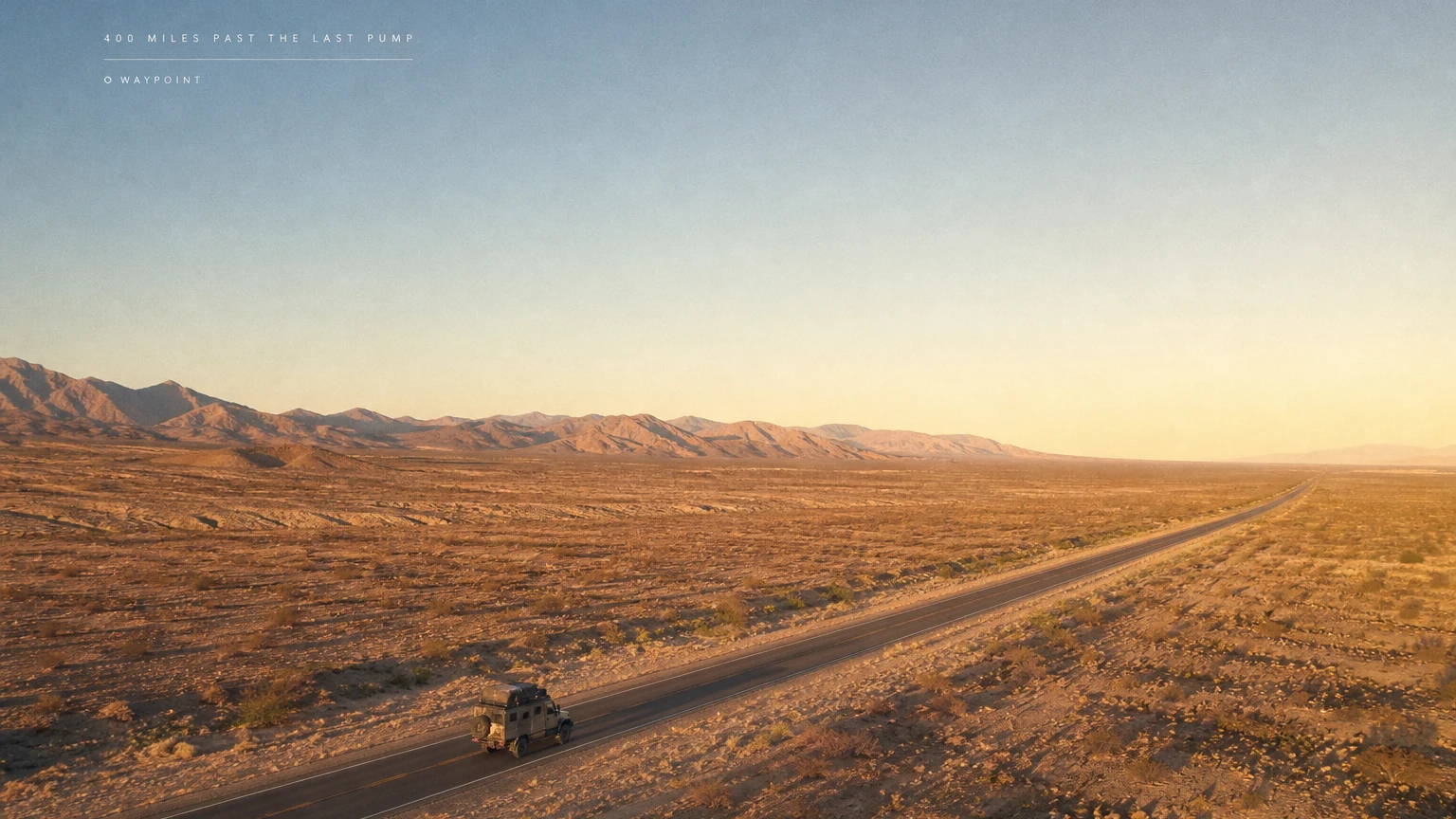 A dead-straight desert highway at golden hour with a single expedition truck, a tiny tracked-out caption line high in the sky.