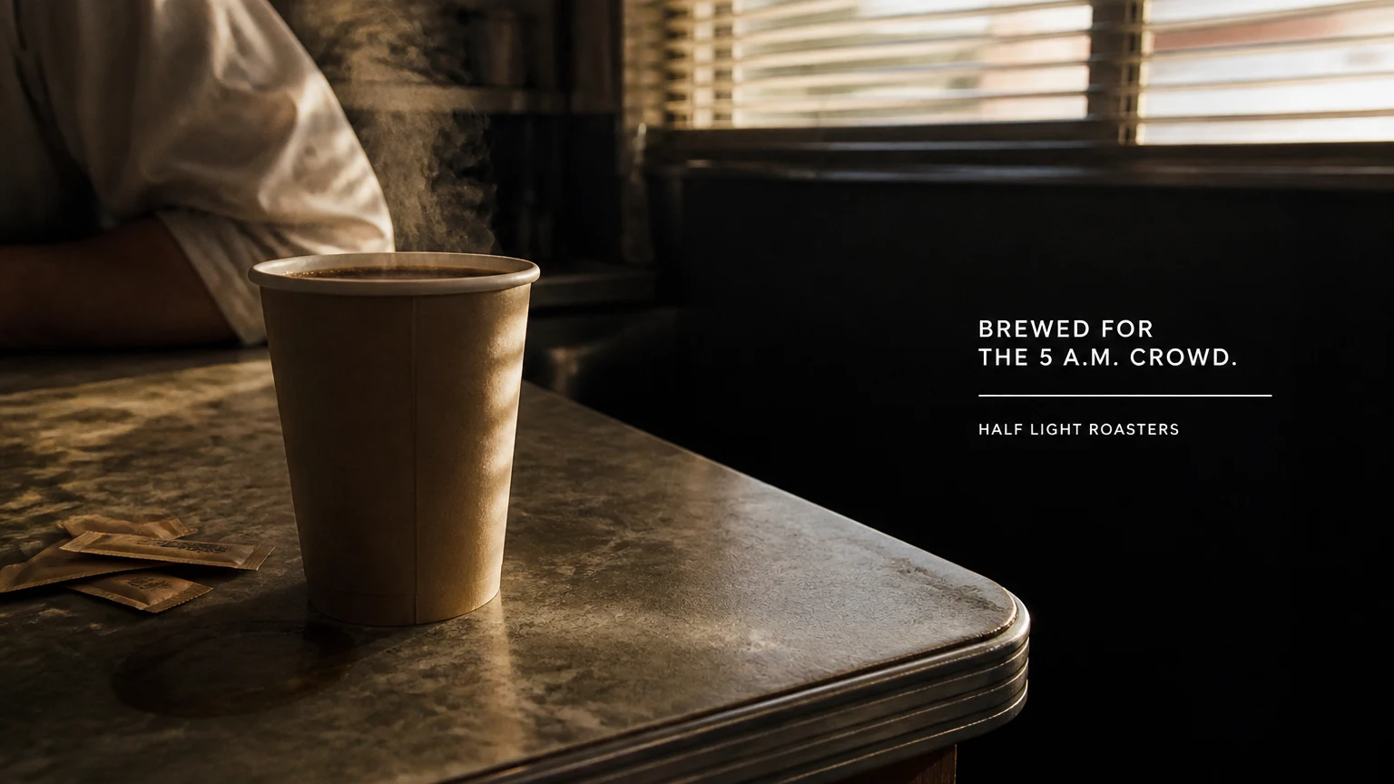 A steaming paper cup on a worn diner counter at dawn, a small typeset headline and wordmark in the shadowed right of the frame.